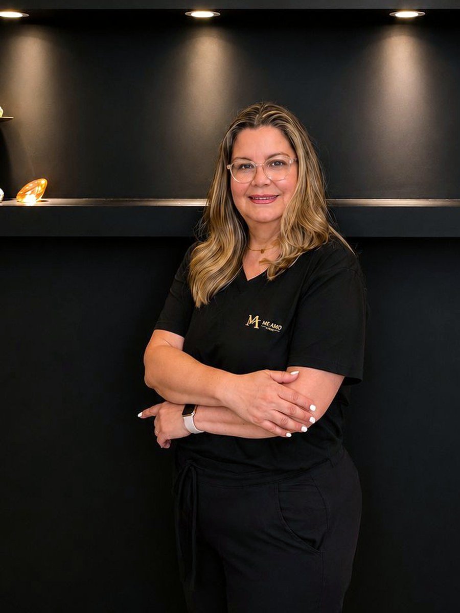 Wendy, del equipo de Me Amo Clinic, en la recepción bajo el logotipo dorado